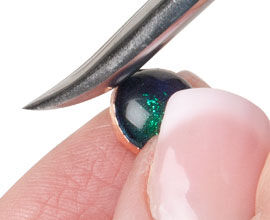 Foil being pressed onto cabochon with burnisher